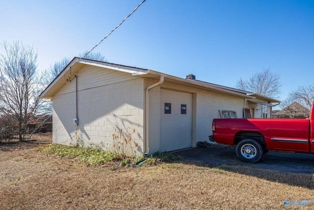 view of property exterior featuring concrete block siding and a chimney