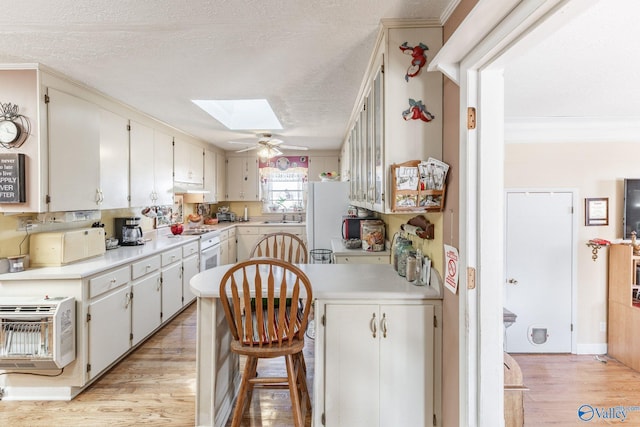 kitchen featuring a skylight, sink, white cabinets, white appliances, and a textured ceiling