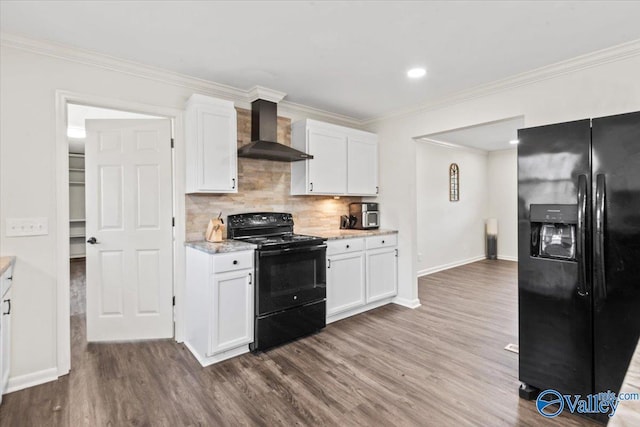 kitchen with black appliances, ornamental molding, dark wood finished floors, white cabinets, and wall chimney range hood
