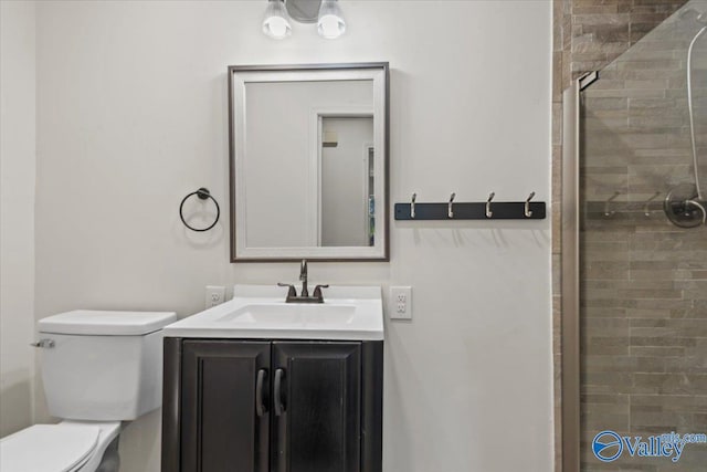 bathroom featuring toilet, tiled shower, and vanity