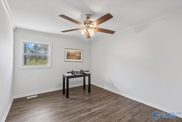 empty room featuring dark wood finished floors, crown molding, and baseboards