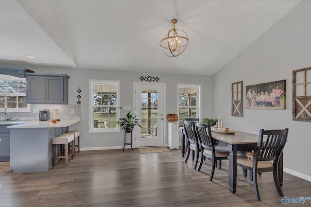 dining area featuring a notable chandelier, dark hardwood / wood-style floors, lofted ceiling, and sink