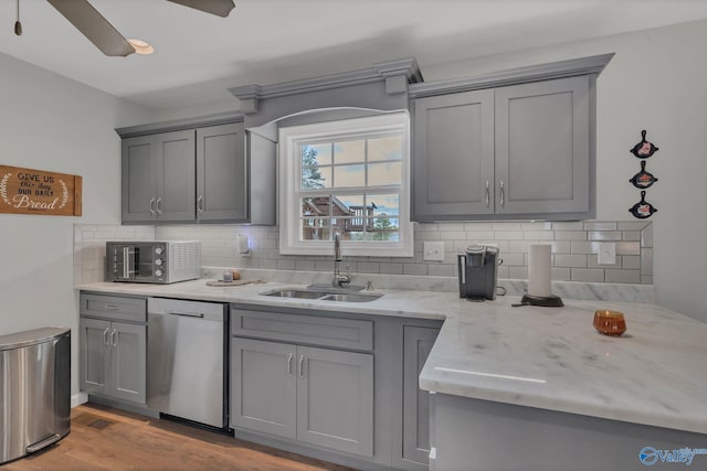 kitchen with ceiling fan, sink, tasteful backsplash, stainless steel dishwasher, and light wood-type flooring