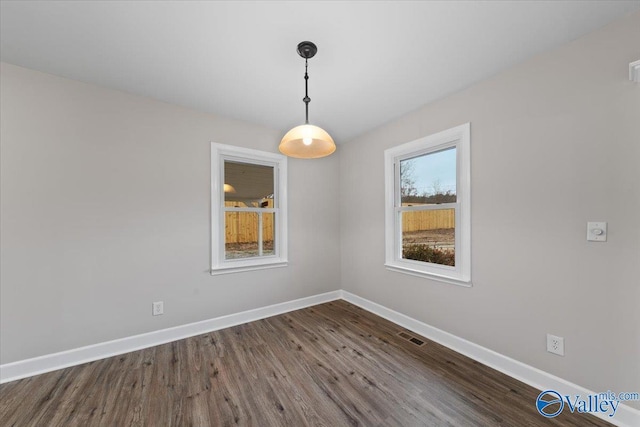 unfurnished room with visible vents, dark wood-type flooring, and baseboards