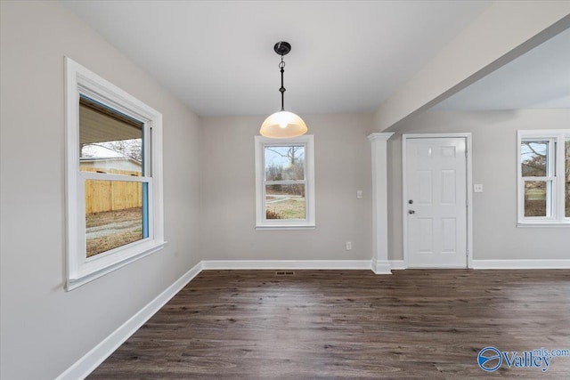 unfurnished dining area with dark wood-type flooring, a healthy amount of sunlight, and baseboards