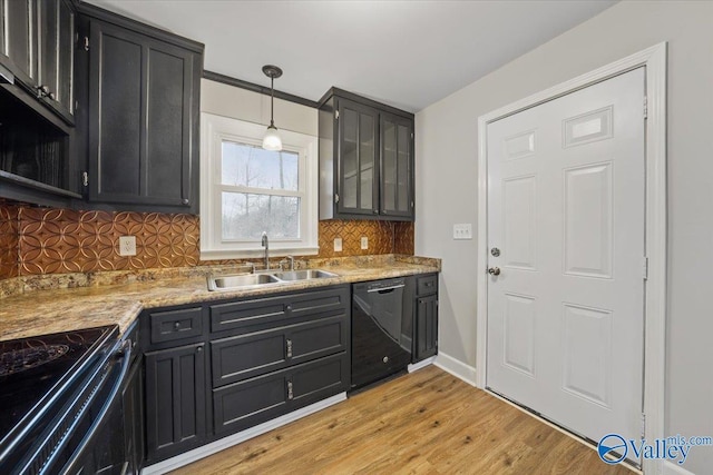 kitchen featuring a sink, backsplash, light wood-style floors, black appliances, and dark cabinets