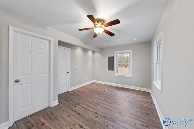 unfurnished bedroom featuring electric panel, wood finished floors, baseboards, and ceiling fan