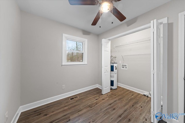 unfurnished bedroom with visible vents, electric water heater, baseboards, dark wood-style floors, and a ceiling fan