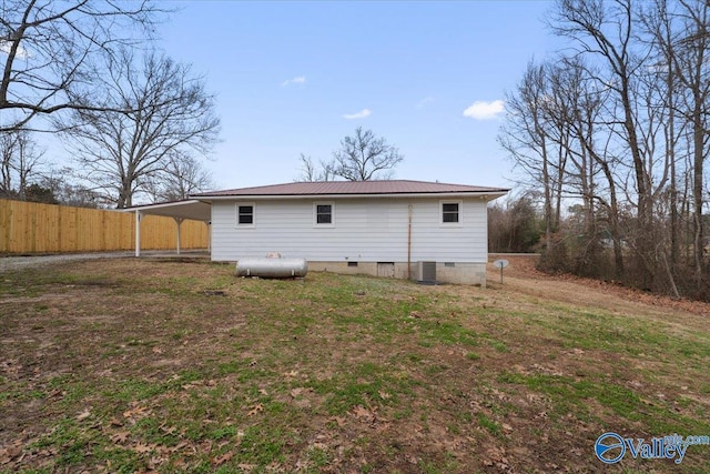 rear view of property with fence, a yard, metal roof, an attached carport, and central AC unit