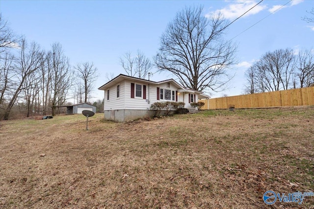 exterior space with an outbuilding, a lawn, and fence