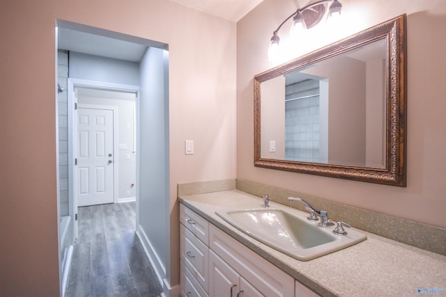 full bathroom featuring a shower, wood finished floors, vanity, and baseboards