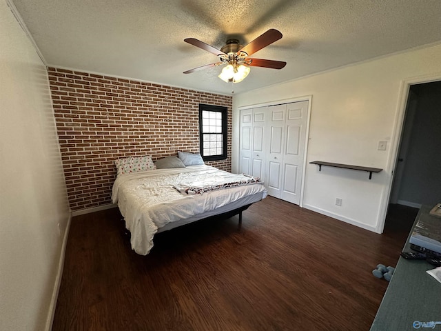 bedroom with brick wall, a textured ceiling, dark hardwood / wood-style flooring, and a closet