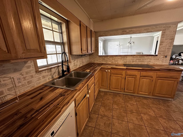 kitchen with sink, butcher block countertops, tasteful backsplash, white dishwasher, and pendant lighting