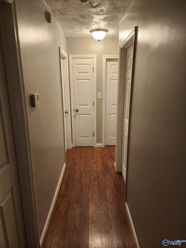 hallway featuring dark hardwood / wood-style floors and a textured ceiling