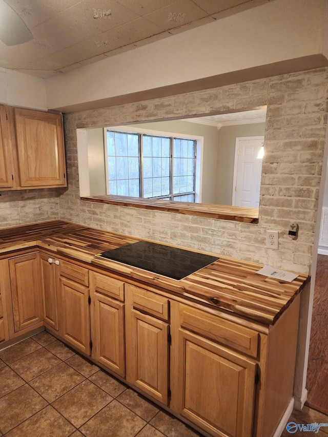 kitchen featuring tasteful backsplash, black electric stovetop, light tile patterned floors, and kitchen peninsula