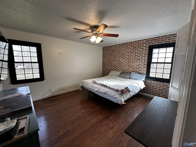 bedroom with ceiling fan, brick wall, dark hardwood / wood-style floors, and a textured ceiling