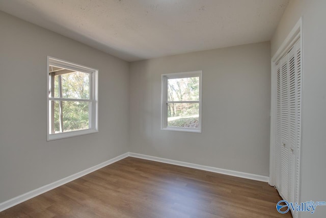 unfurnished bedroom featuring wood-type flooring, a closet, and multiple windows