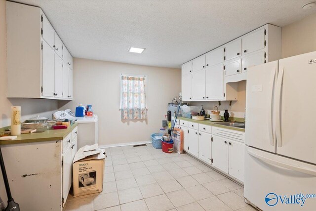 kitchen featuring white cabinets, a textured ceiling, and white fridge