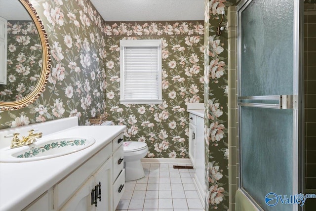 full bathroom featuring a textured ceiling, vanity, shower / bath combination with glass door, tile patterned flooring, and toilet