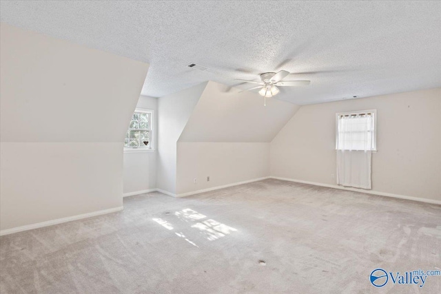 additional living space with light carpet, a textured ceiling, ceiling fan, and lofted ceiling