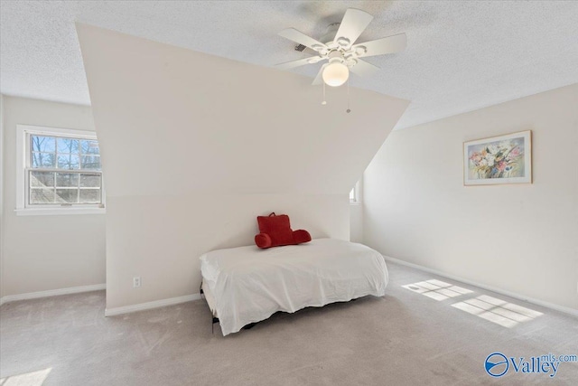 bedroom featuring a textured ceiling, light colored carpet, and ceiling fan