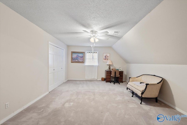 sitting room featuring ceiling fan, lofted ceiling, a textured ceiling, and light carpet