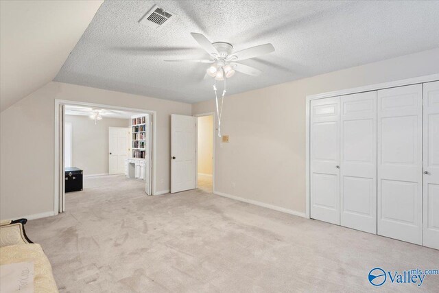 unfurnished bedroom featuring light carpet, a closet, vaulted ceiling, and ceiling fan