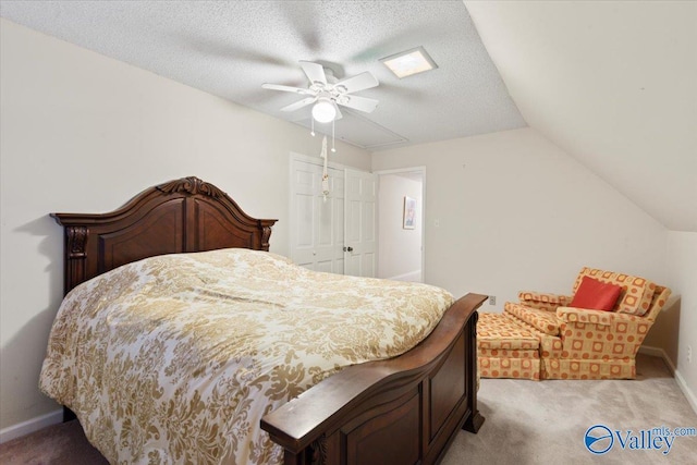 carpeted bedroom with ceiling fan, lofted ceiling, a textured ceiling, and a closet