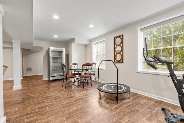 living area with ornamental molding, hardwood / wood-style flooring, and ornate columns