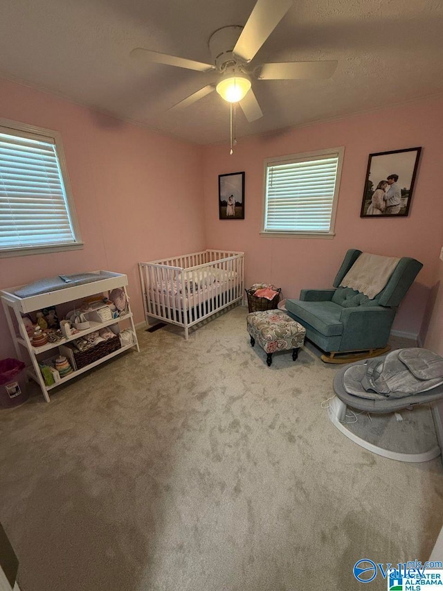 bedroom with carpet flooring, a nursery area, and ceiling fan