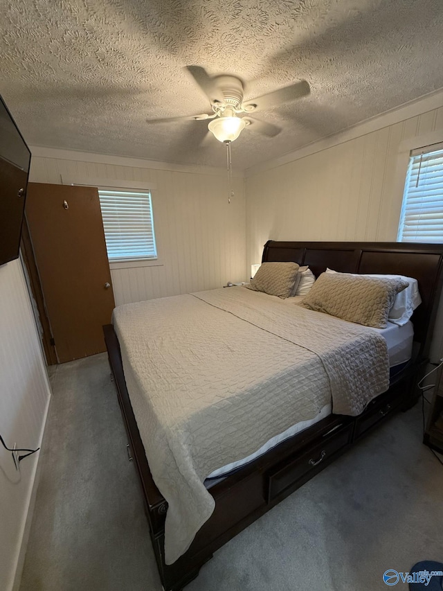 carpeted bedroom featuring multiple windows, a textured ceiling, ceiling fan, and crown molding