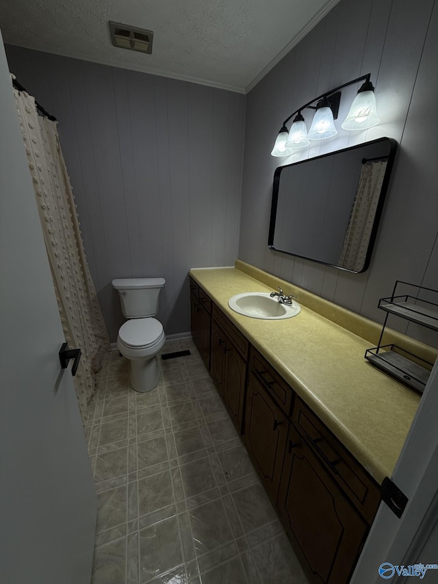 bathroom with wood walls, vanity, a textured ceiling, and toilet