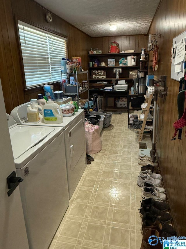 laundry area with a textured ceiling, wooden walls, and washing machine and clothes dryer