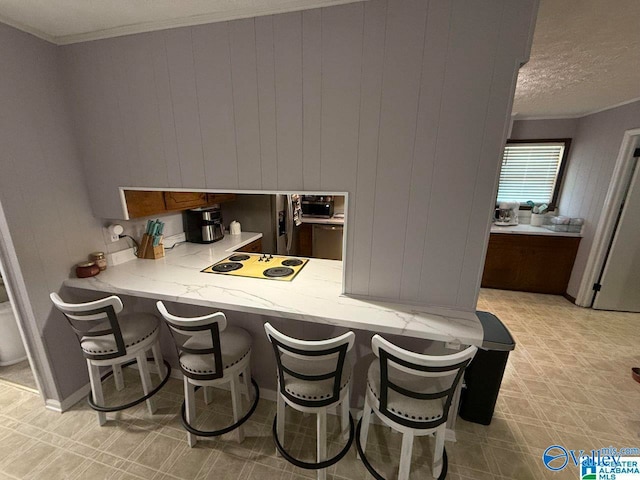 bar featuring light stone countertops, ornamental molding, a textured ceiling, white electric cooktop, and wood walls