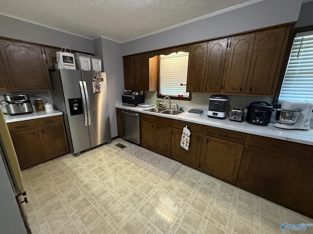 kitchen featuring appliances with stainless steel finishes, dark brown cabinets, a textured ceiling, crown molding, and sink