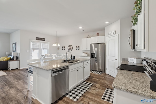 kitchen with stainless steel appliances, decorative light fixtures, sink, and a kitchen island with sink