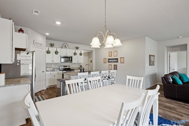 dining space with sink, dark hardwood / wood-style flooring, and an inviting chandelier