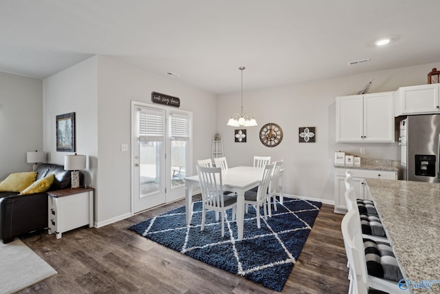 dining room with dark hardwood / wood-style flooring and a chandelier