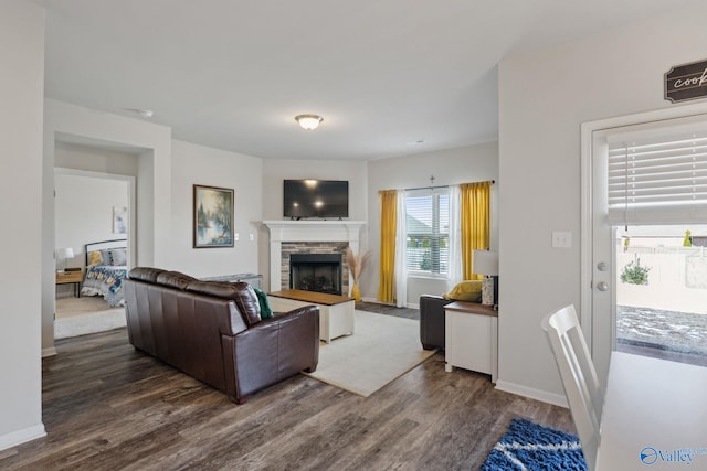 living room with dark wood-type flooring and a stone fireplace