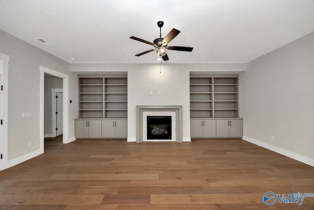 unfurnished living room featuring a fireplace, wood finished floors, visible vents, and baseboards