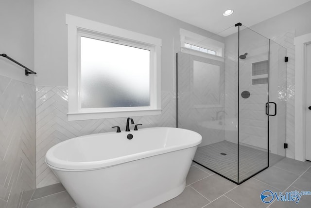 full bath featuring a stall shower, a freestanding bath, tile walls, and tile patterned floors