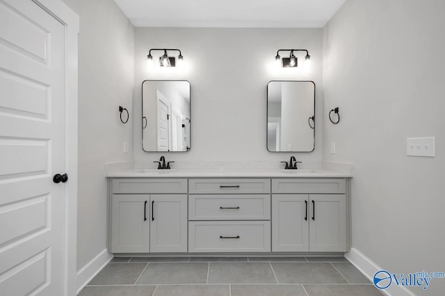 bathroom with double vanity, baseboards, and a sink