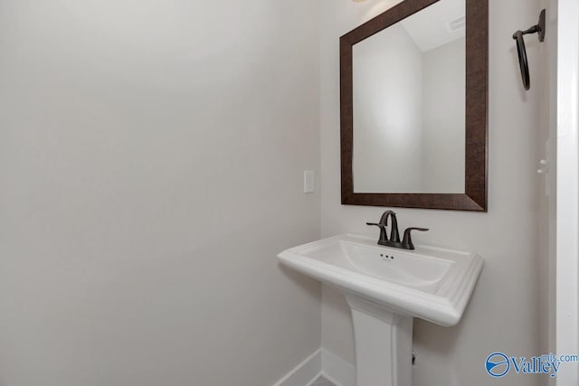 bathroom with a sink, visible vents, and baseboards