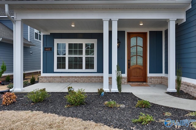 property entrance with a porch, board and batten siding, and brick siding