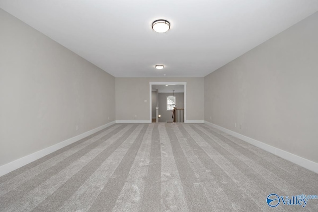 empty room featuring baseboards and light colored carpet