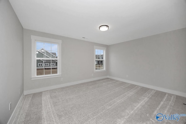 spare room with carpet flooring, visible vents, and baseboards