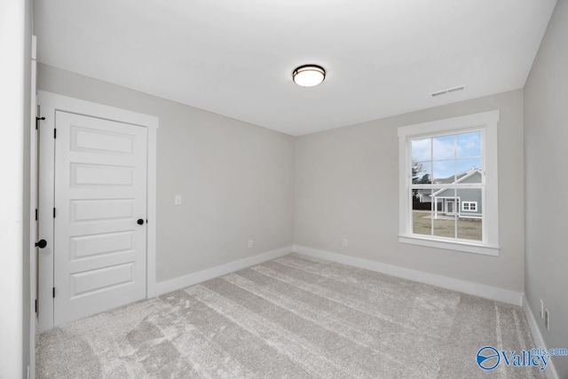 carpeted spare room with visible vents and baseboards