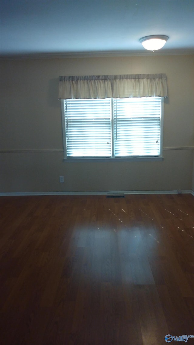 unfurnished room featuring visible vents, wood finished floors, and baseboards