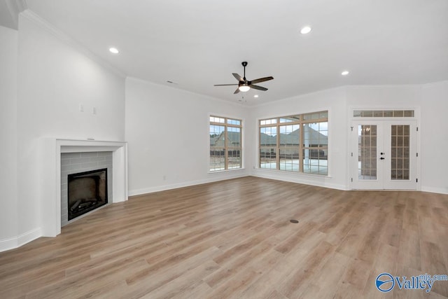 unfurnished living room featuring crown molding, light hardwood / wood-style flooring, a fireplace, and french doors