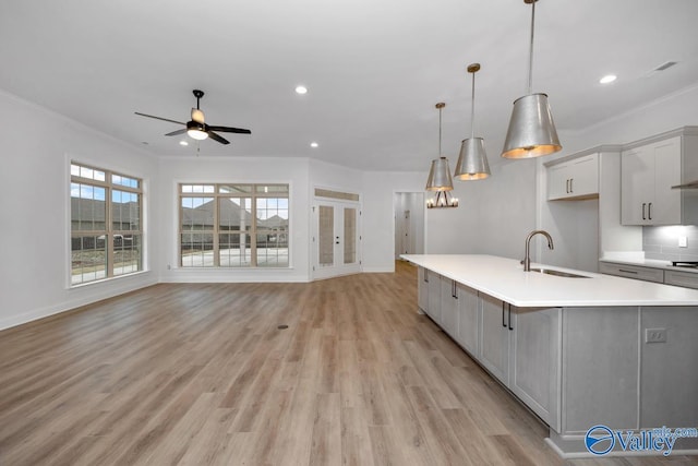 kitchen with pendant lighting, a large island, sink, and light hardwood / wood-style flooring